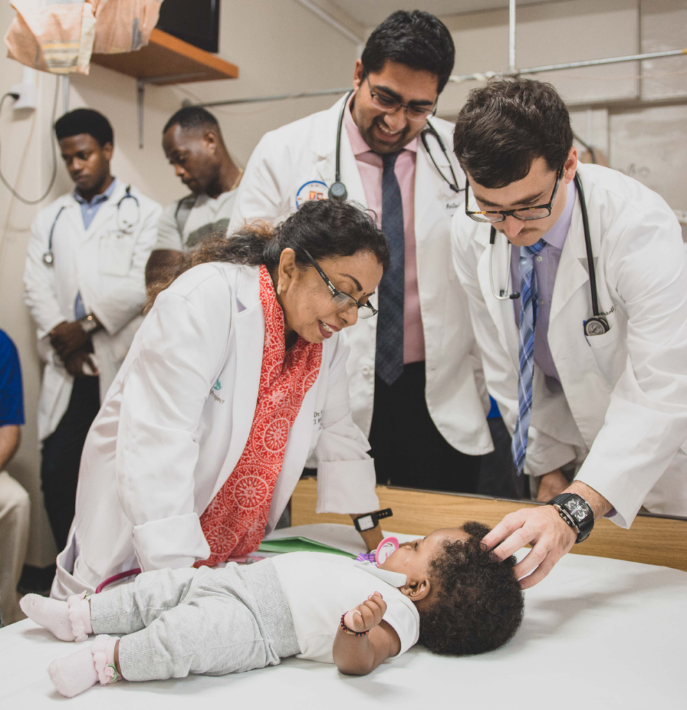 Trinity medical school students in a clinical lab observing a young child