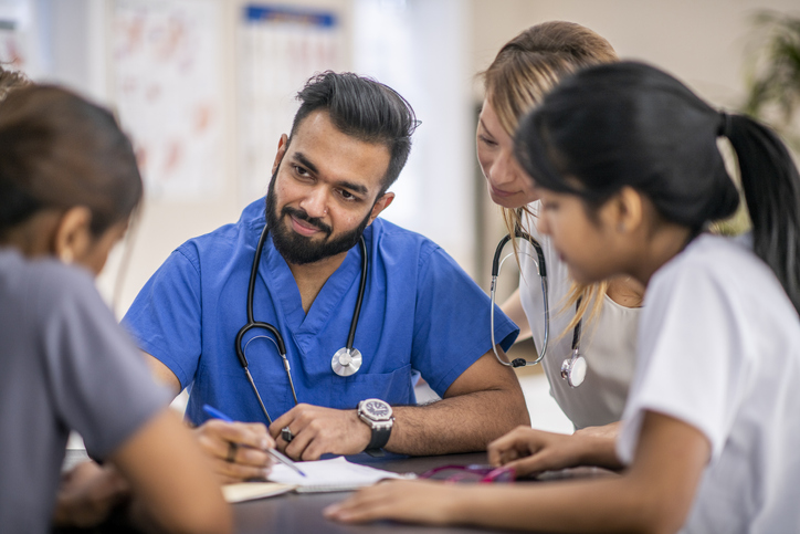 Medical residents meet with their team lead in between working with patients