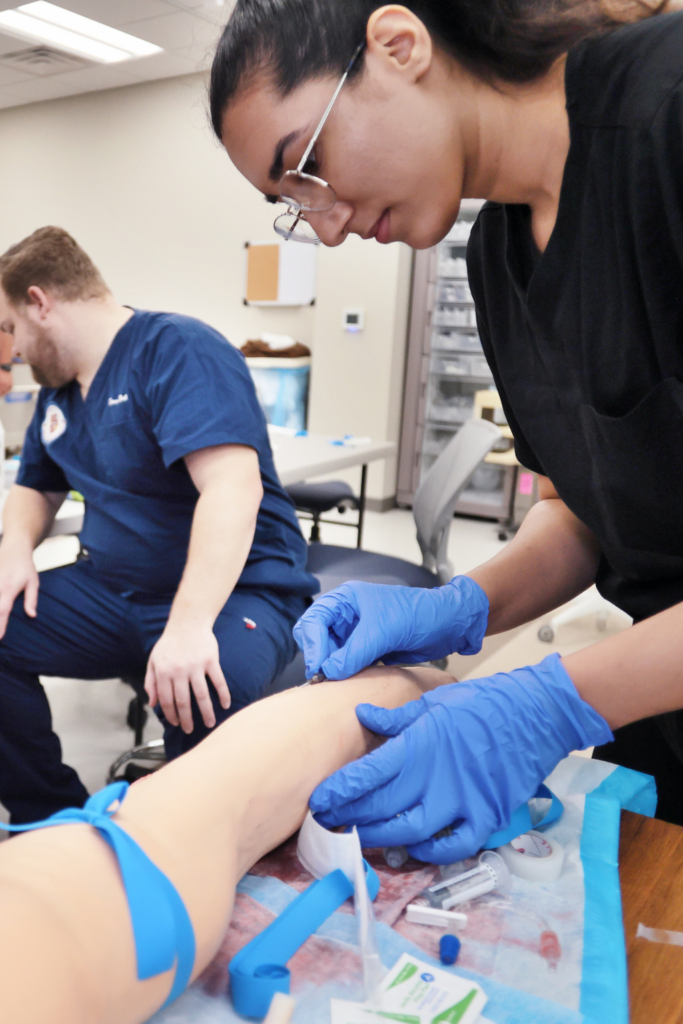 Closeup of medical school students placing an IV in a patient's arm